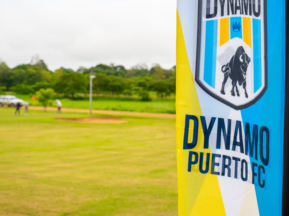 Bandera de Dynamo Puerto FC junto a una cancha de fútbol